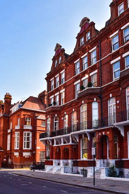 A detailed exterior view of a Victorian residential building showing ornate white stone and red brick façade, including decorative columns, arches, and cornices. The building features tall windows wi